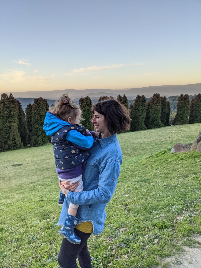 Jeneile with her daughter with a sunset and mountains in the background 