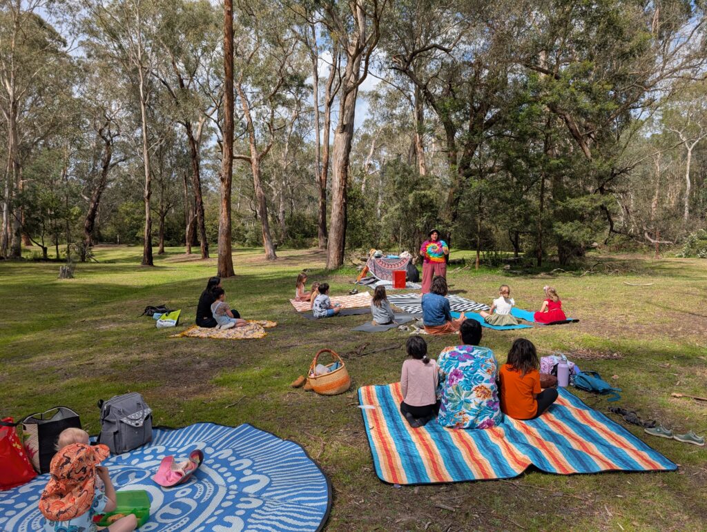 Homeschool families outside on picnic rugs together in the forest