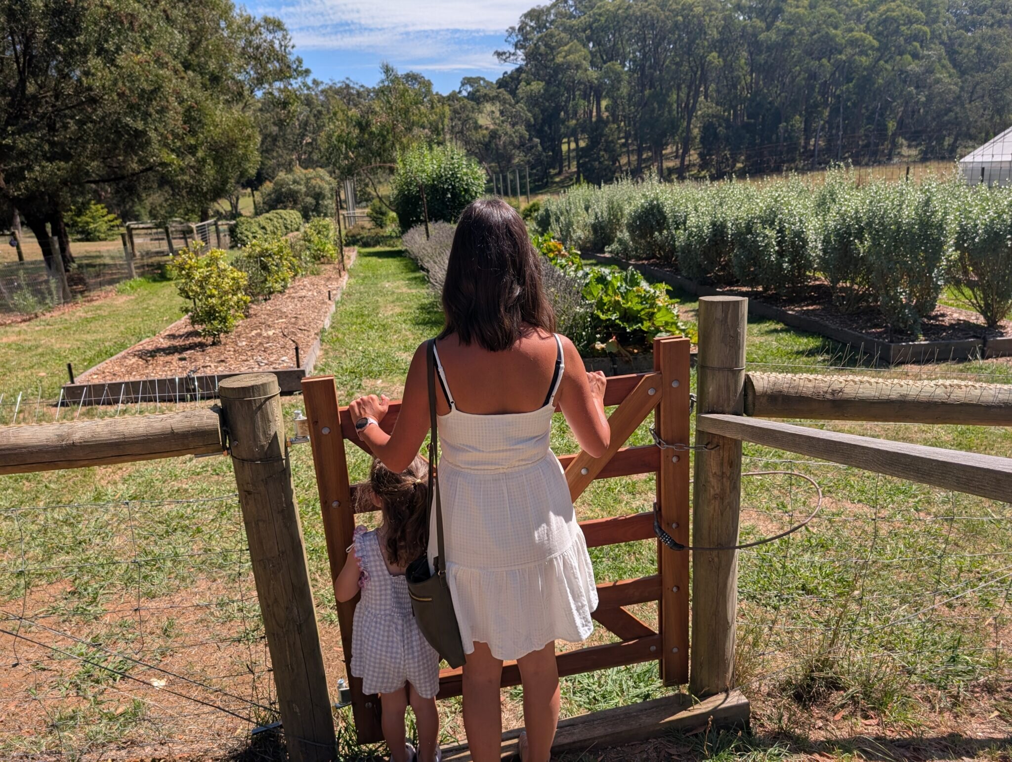 Mother and child outside at a gate within the sunshine and greenery